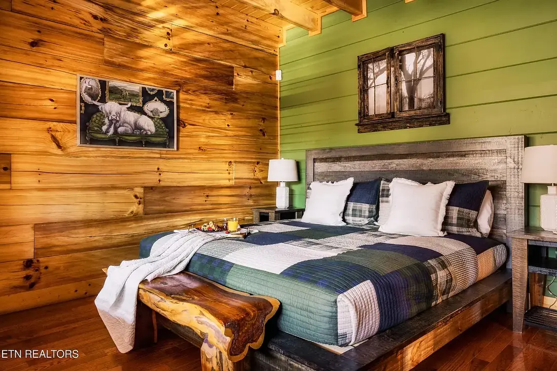 King bedroom with green accent wall, reclaimed wood headboard and a live-edge wooden bench at the foot of the bed