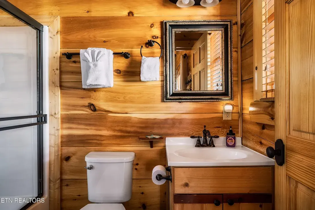 Full bathroom with walk-in shower, framed mirror, vanity and wood plank walls